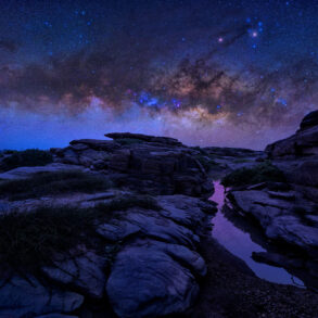 Starry sky over canyon with water