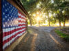 Afternoon light through the trees with American flag painted on barn