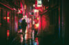 Person with umbrella in rainy alley in Japan with glow or red lights