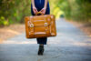 Woman holding suitcase on empty, bright road