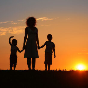 Silhouette of mother with children at sunset