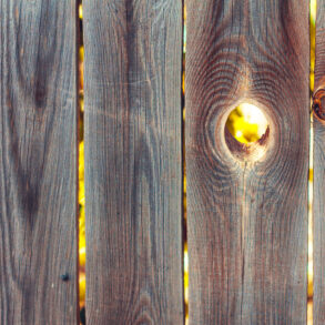 Backlit hole in wooden fence