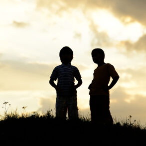 Silhouette of two boys on a hill