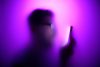 Unfocused photo of man holding phone with pink glow