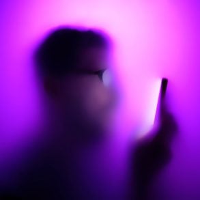 Unfocused photo of man holding phone with pink glow