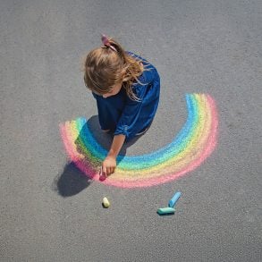 Girl drawing with chalk on sidewalk
