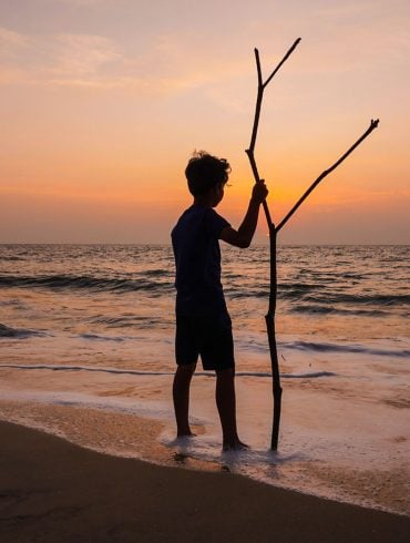 Silhouette of boy with stick on beach of Indian Ocean