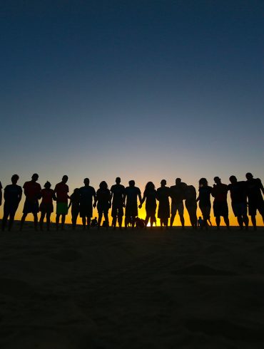 Line of people silhouetted against rising sun